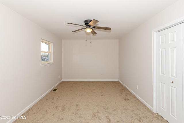 empty room featuring ceiling fan and light colored carpet