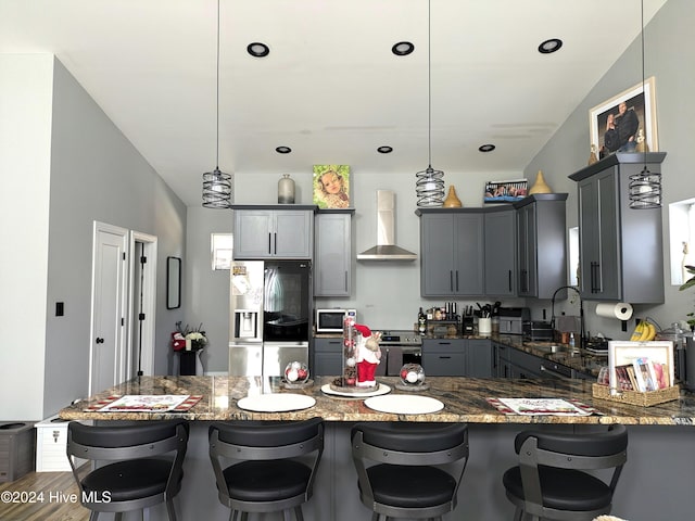 kitchen featuring wall chimney exhaust hood, sink, hanging light fixtures, and stainless steel appliances