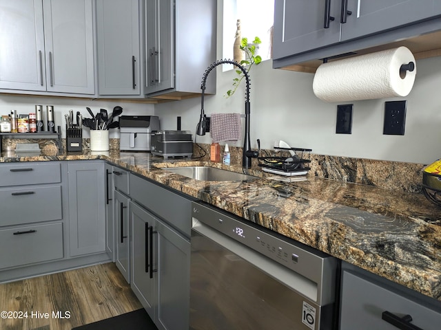 kitchen with dishwasher, dark stone counters, dark hardwood / wood-style floors, and sink