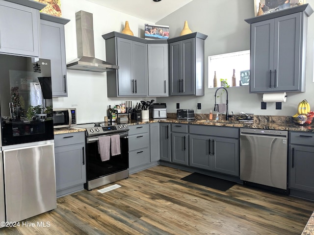 kitchen with appliances with stainless steel finishes, gray cabinets, wall chimney exhaust hood, and sink