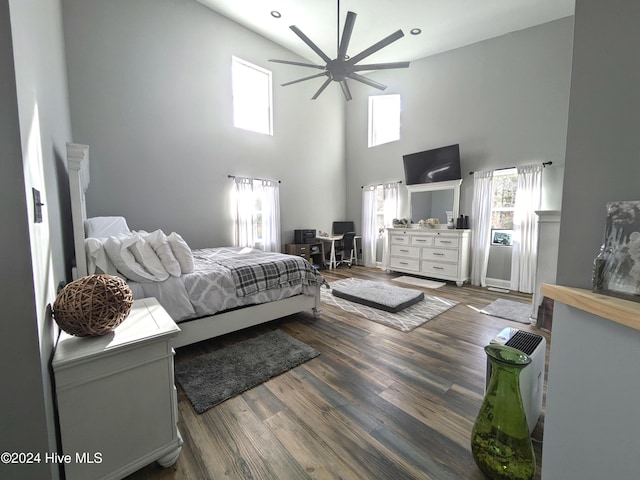 bedroom featuring ceiling fan, dark hardwood / wood-style flooring, and a towering ceiling