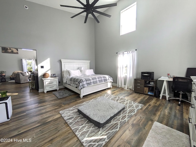 bedroom with ceiling fan, dark wood-type flooring, and a high ceiling