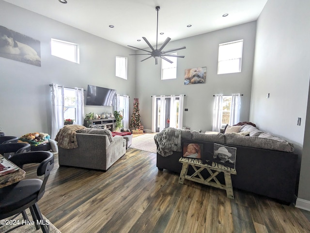 living room featuring ceiling fan, dark wood-type flooring, and a high ceiling