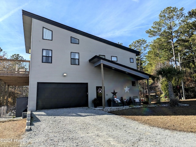 rear view of house featuring a deck and a garage