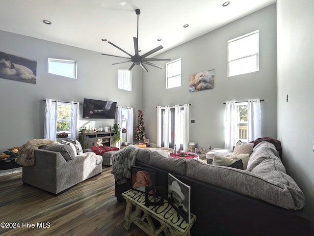 living room with ceiling fan, dark hardwood / wood-style floors, and a towering ceiling