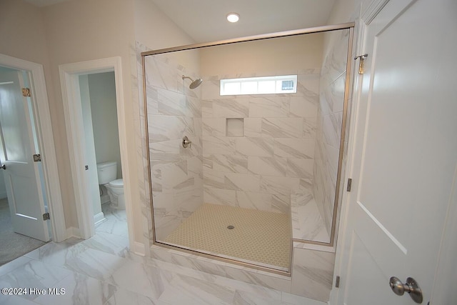 bathroom with a tile shower and toilet