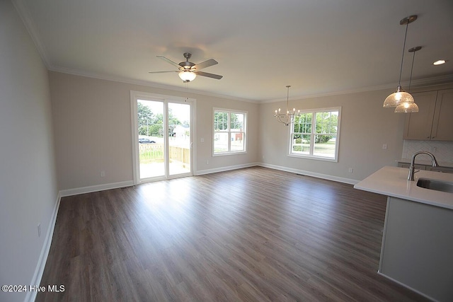 unfurnished living room with sink, dark hardwood / wood-style floors, ceiling fan with notable chandelier, and ornamental molding