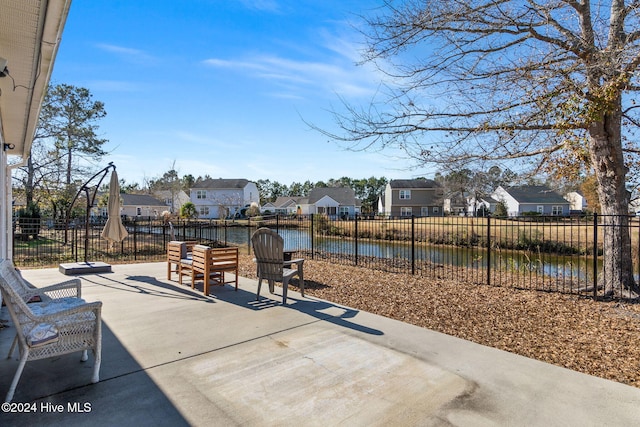 view of patio with a residential view, fence, and a water view