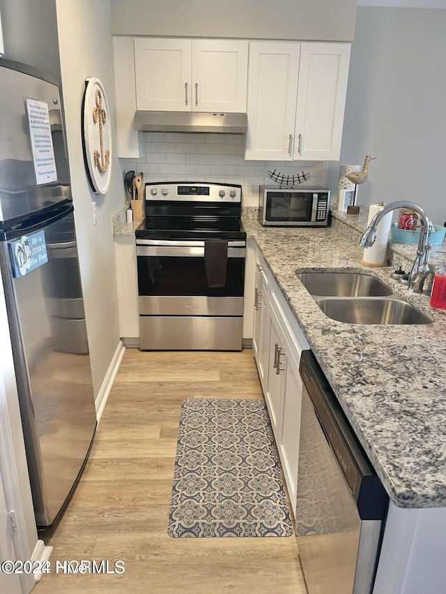 kitchen with white cabinets, sink, decorative backsplash, appliances with stainless steel finishes, and light hardwood / wood-style floors