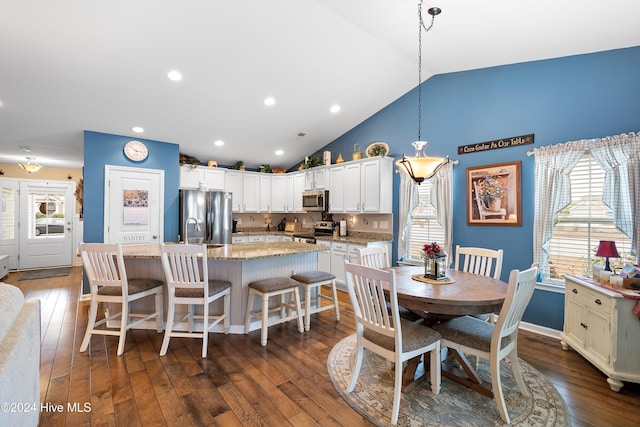 dining room featuring sink, high vaulted ceiling, and dark wood-type flooring