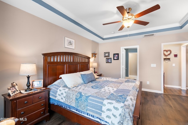 bedroom with dark hardwood / wood-style flooring, a tray ceiling, ceiling fan, and crown molding