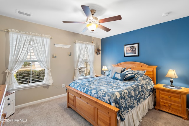 bedroom featuring ceiling fan, light carpet, and multiple windows