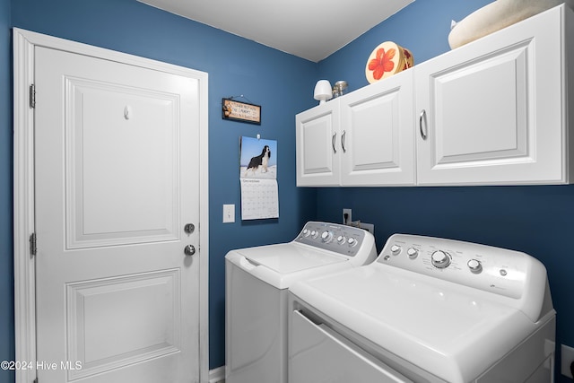 clothes washing area featuring washer and clothes dryer and cabinets