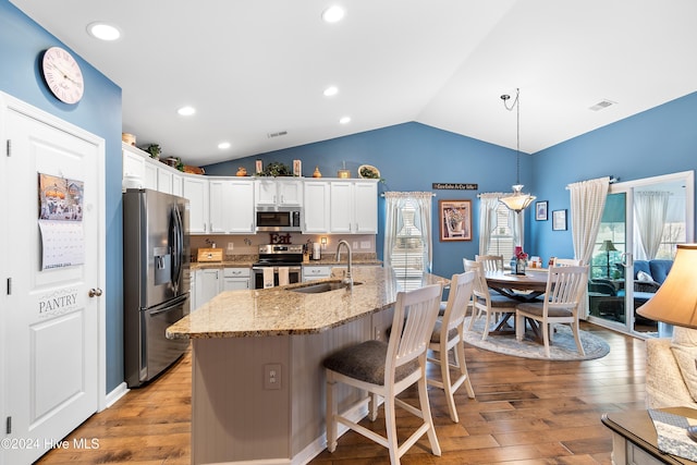 kitchen with sink, white cabinets, stainless steel appliances, and decorative light fixtures