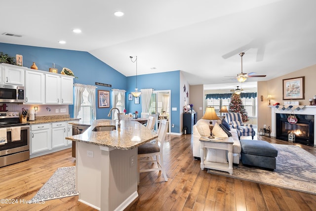 kitchen featuring sink, light stone counters, pendant lighting, white cabinets, and appliances with stainless steel finishes