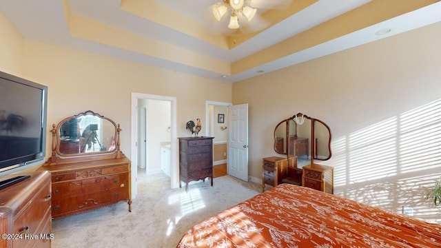 bedroom with connected bathroom, a raised ceiling, and ceiling fan