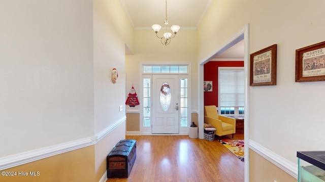 foyer entrance with a chandelier, hardwood / wood-style floors, and crown molding