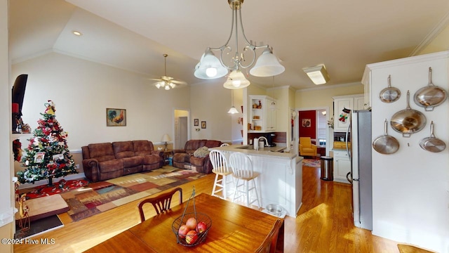 dining area with sink, crown molding, light hardwood / wood-style floors, lofted ceiling, and ceiling fan with notable chandelier