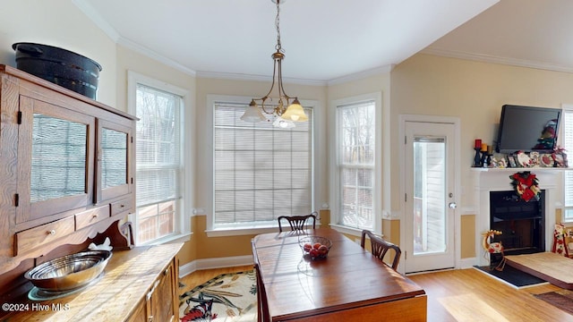 dining space with light wood-type flooring, an inviting chandelier, and ornamental molding