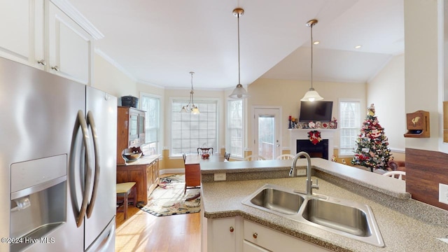 kitchen with pendant lighting, white cabinets, sink, light hardwood / wood-style flooring, and stainless steel fridge with ice dispenser