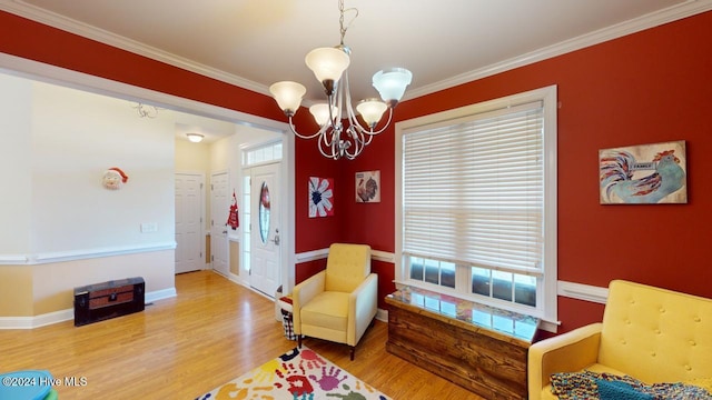 sitting room featuring hardwood / wood-style floors, crown molding, a wealth of natural light, and an inviting chandelier