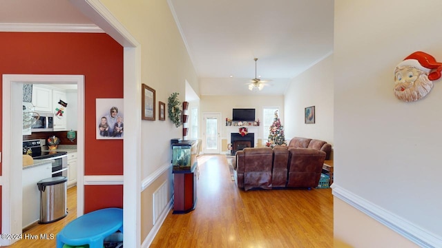 hall with light hardwood / wood-style floors and ornamental molding