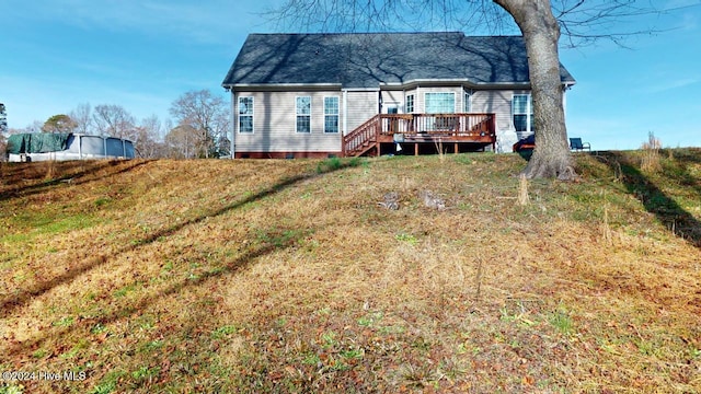 back of house featuring a lawn and a deck