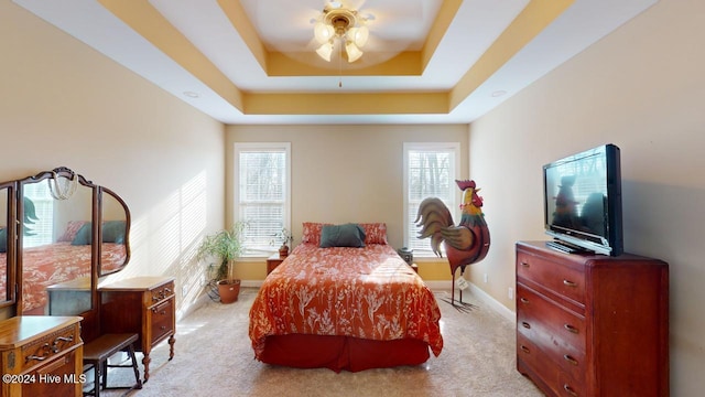 bedroom featuring light carpet, a tray ceiling, and ceiling fan