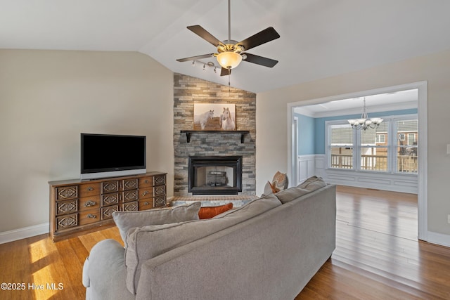 living room featuring lofted ceiling, a fireplace, ceiling fan with notable chandelier, and light wood-type flooring