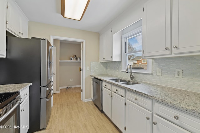 kitchen with appliances with stainless steel finishes, tasteful backsplash, white cabinetry, sink, and light stone counters