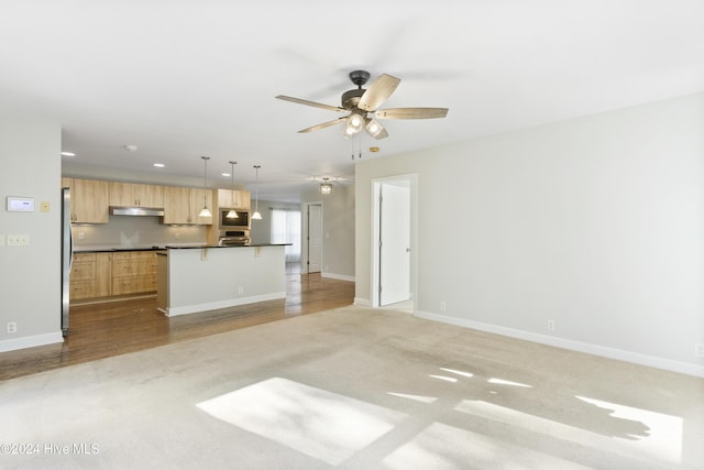 unfurnished living room featuring ceiling fan and light colored carpet