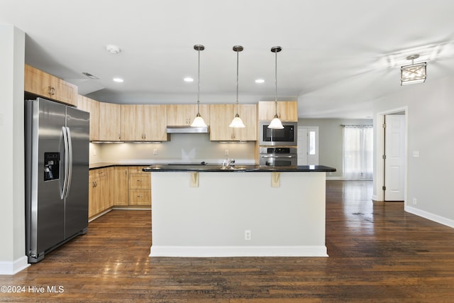 kitchen with appliances with stainless steel finishes, a kitchen breakfast bar, light brown cabinetry, a center island with sink, and hanging light fixtures