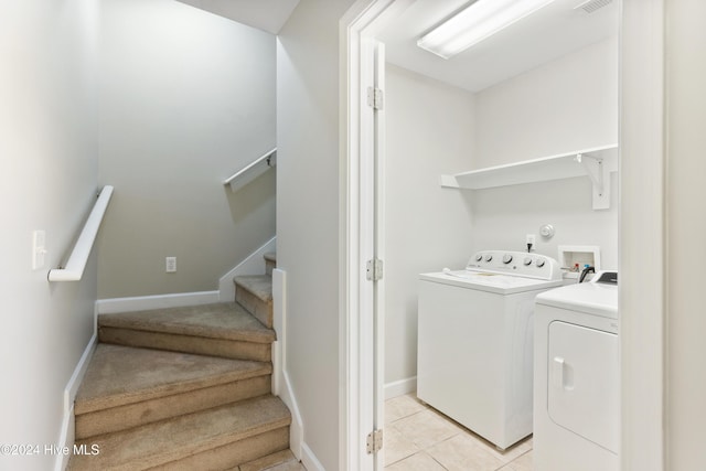 clothes washing area with light tile patterned floors and washer and clothes dryer