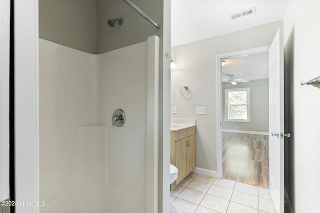 bathroom featuring ceiling fan, walk in shower, tile patterned flooring, toilet, and vanity