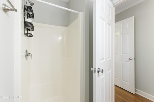 bathroom with a shower, hardwood / wood-style floors, and ornamental molding