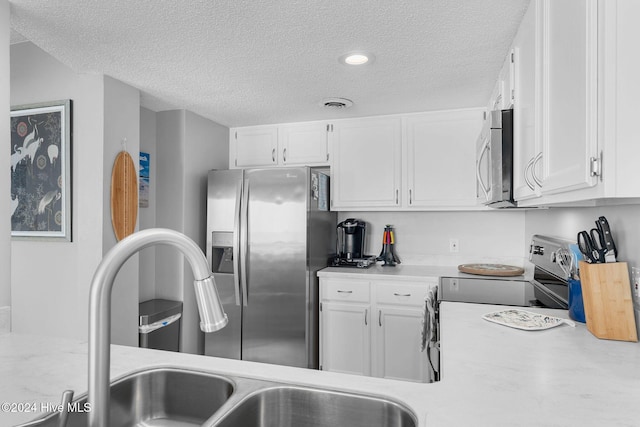 kitchen with appliances with stainless steel finishes, a textured ceiling, and white cabinetry