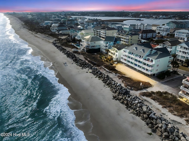 aerial view at dusk featuring a view of the beach and a water view