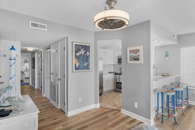 hallway with a textured ceiling and light wood-type flooring