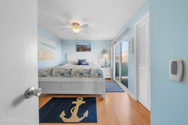 bedroom featuring a textured ceiling, light wood-type flooring, a closet, and ceiling fan