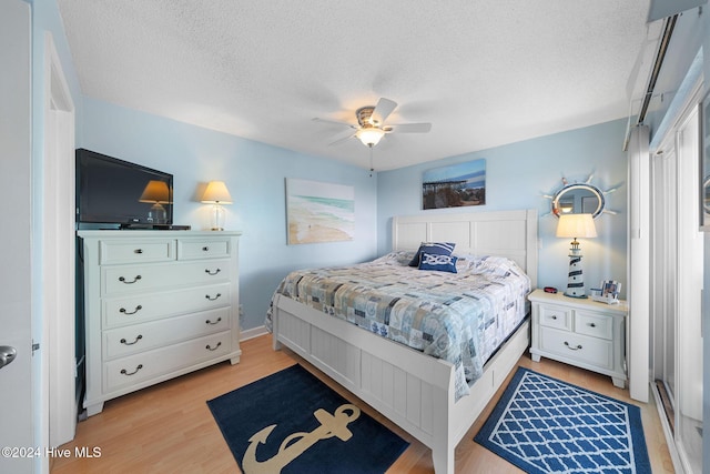 bedroom with ceiling fan, light hardwood / wood-style floors, and a textured ceiling