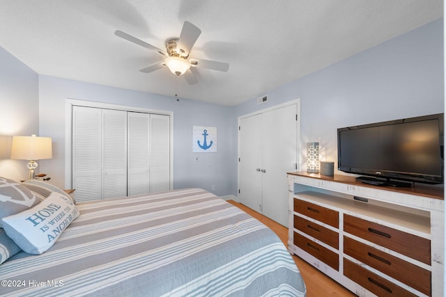 bedroom with ceiling fan, light hardwood / wood-style floors, a textured ceiling, and a closet