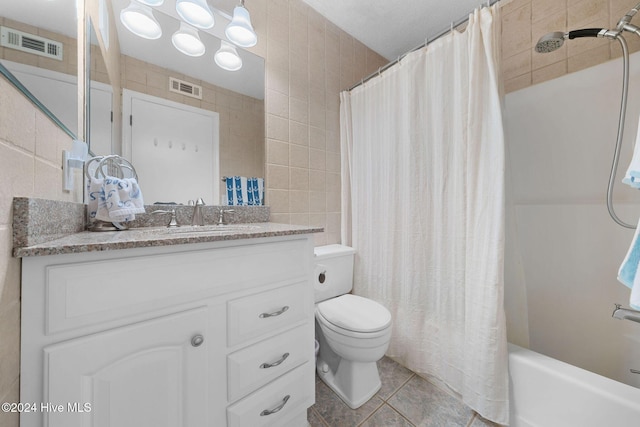 full bathroom with shower / bath combination with curtain, vanity, tile walls, tile patterned flooring, and toilet