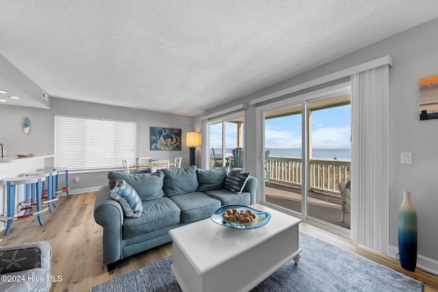 living room featuring a water view, a textured ceiling, and hardwood / wood-style flooring