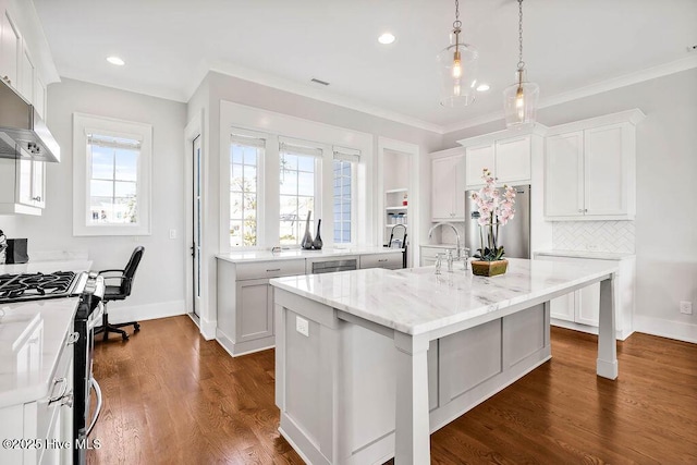 kitchen featuring white cabinetry, a kitchen island with sink, light stone counters, and appliances with stainless steel finishes