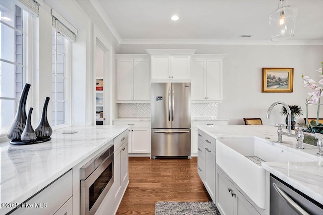 kitchen featuring backsplash, white cabinets, decorative light fixtures, and appliances with stainless steel finishes