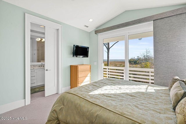 bedroom with ensuite bath, light colored carpet, and lofted ceiling