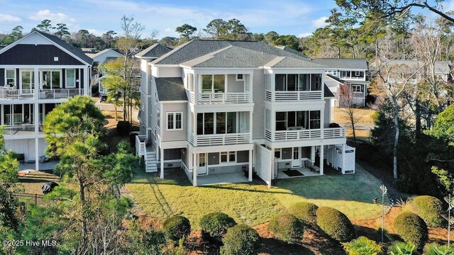 back of property with a yard, a balcony, and a patio