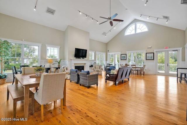 dining space featuring ceiling fan, french doors, light hardwood / wood-style floors, and a high ceiling