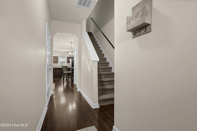 hallway featuring dark hardwood / wood-style floors and an inviting chandelier