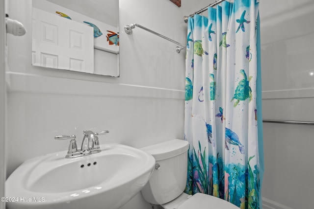 bathroom featuring toilet, curtained shower, and sink